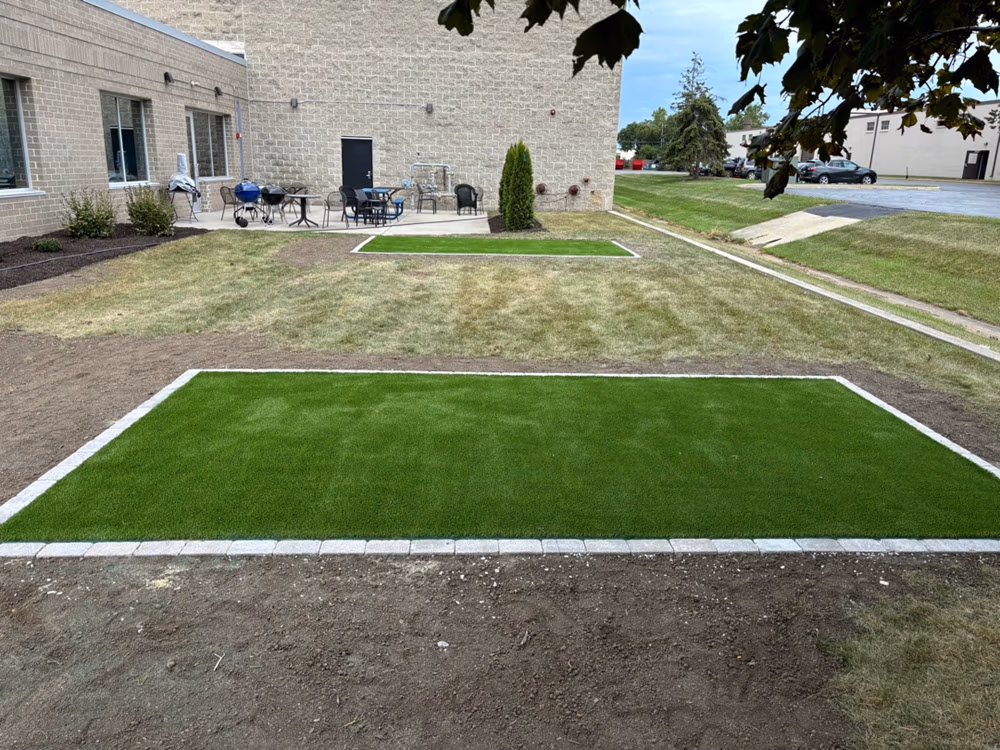 Artificial turf installation featuring cornhole boards set up for employee recreational use. The area is designed with a lush, green synthetic grass for easy play and enjoyment.