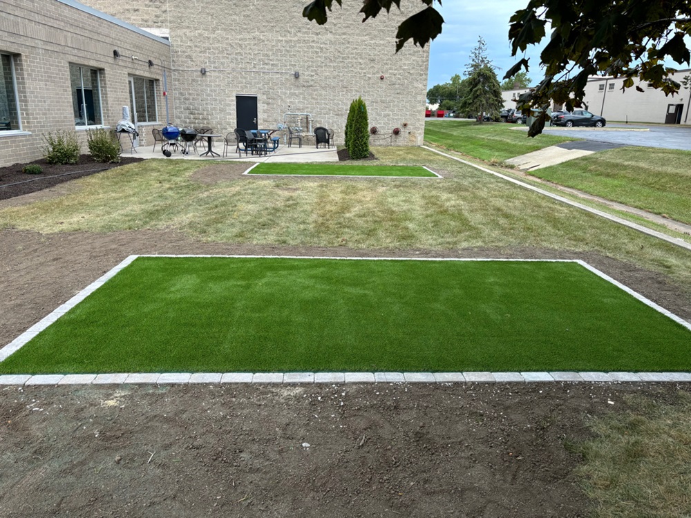 Artificial turf installation featuring cornhole boards set up for employee recreational use. The area is designed with a lush, green synthetic grass for easy play and enjoyment.