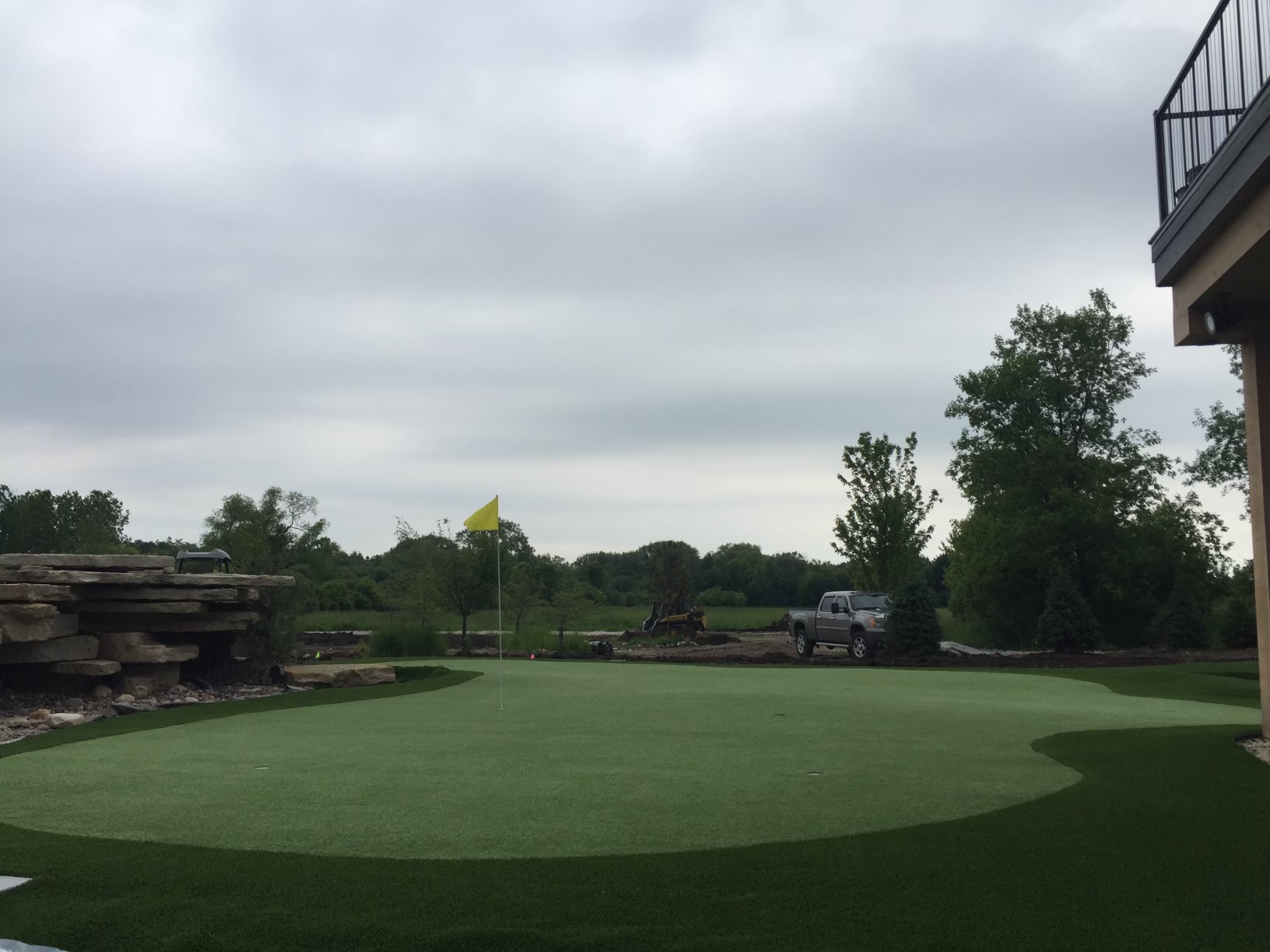 Custom backyard putting green with artificial turf and stone retaining wall in Wisconsin