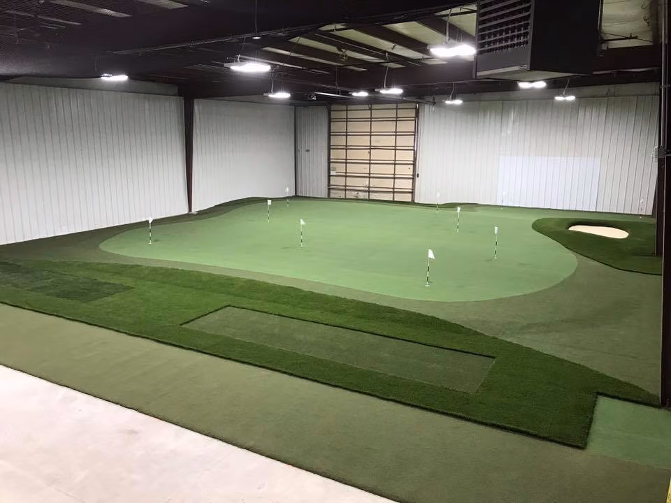 Large indoor golf complex putting green with fringe and sand bunker area by Premier Turf & Greens.
