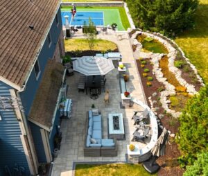 Aerial view of a luxury backyard featuring a custom blue and green synthetic turf pickleball court and professional landscaping